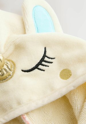Ručník s kapuljačom od kremastog teksturiranog materijala, s metalik zlatnim naglaskom, izvezenim dizajnom zatvorenog oka i detaljima u svijetloplavoj boji na ušima.