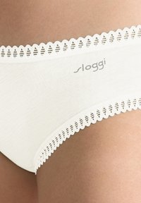 Perizoma bianco in cotone con bordo in pizzo a onde e logo "sloggi". Texture liscia con leggera elasticità per una vestibilità comoda.