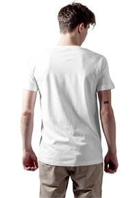 White cotton T-shirt with a round neck, short sleeves, and smooth texture, viewed from the back. Subtle branding at the neck.