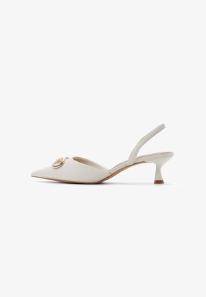 Witte leren slingback kittenheel met spitse neus en gouden ronde gespdetail aan de voorkant.