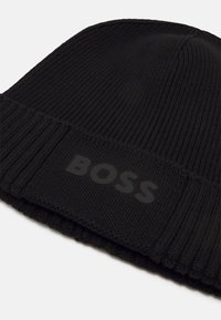 Black knit beanie with ribbed texture and a fold-over cuff. Features a matte black "BOSS" logo on the front. Soft, warm material.