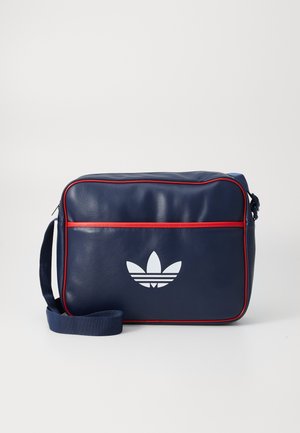 Borsa in similpelle blu navy con piping rosso, tracolla regolabile e logo bianco sul davanti. Forma rettangolare con chiusura a zip.