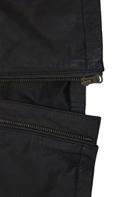Svart läderjacka med dubbla dragkedjefickor, texturerad yta och en strukturerad design. Synlig mässingsdetaljer kompletterar materialet.