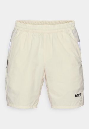 Beige swim shorts with an elastic waistband, side pockets, and a black logo "BOSS" on the bottom right. Smooth, lightweight fabric.