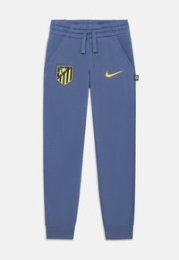 Blaue sportliche Jogginghosen mit elastischem Bund, Seitentaschen, gelbem Nike-Logo und dem Vereinsemblema von Atlético Madrid auf dem linken Oberschenkel.