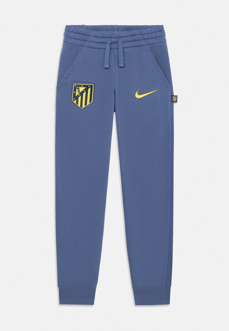Blaue sportliche Jogginghosen mit elastischem Bund, Seitentaschen, gelbem Nike-Logo und dem Vereinsemblema von Atlético Madrid auf dem linken Oberschenkel.