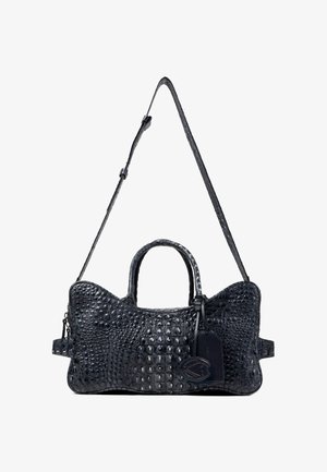 Sac à main en cuir noir texturé avec bandoulière ajustable, deux poignées et étiquette à bagages attachée avec emblème décoratif.