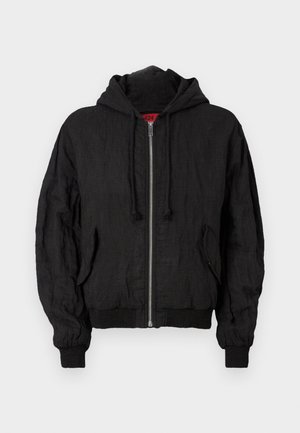 Giacca bomber nera in tessuto leggero, con cappuccio, zip frontale, polsini a costine e vestibilità comoda. Inclusi due taschini laterali.