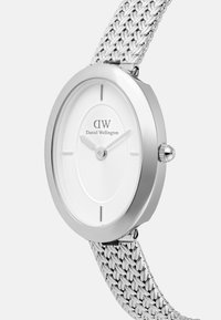 Silver analog watch with a round case and a white dial. Features a textured surface, minimalist hour markers, and a silver woven metal band.