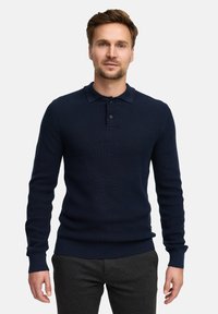 Navyblaues gestricktes Poloshirt mit langen Ärmeln, gerippter Textur und Knopfleiste. Mit eng anliegenden Bündchen und geradem Saum.