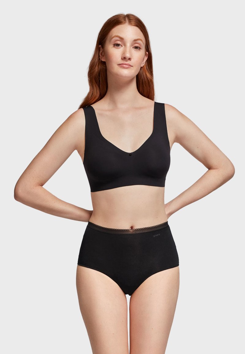 Soutien-gorge sans fil noir avec de larges bretelles et un décolleté en V profond, assorti à des culottes de bikini noires taille haute avec un détail en bordure festonnée.