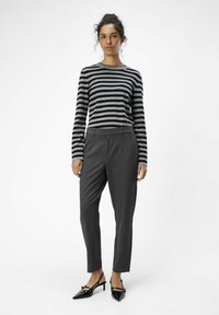 Striped long-sleeve shirt in black and gray, paired with tailored gray trousers. Black patent heels with a pointed toe complete the outfit.