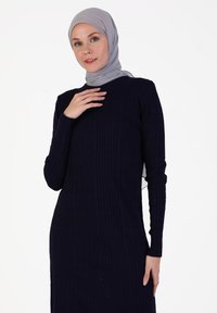 Navy ribbed dress with long sleeves, round neckline, and side slits. Paired with a light gray hijab. Soft knit texture.