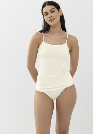 Débardeur en crème clair avec des bretelles fines, présentant une texture lisse et une coupe ajustée, associé à un bas de bikini assorti.
