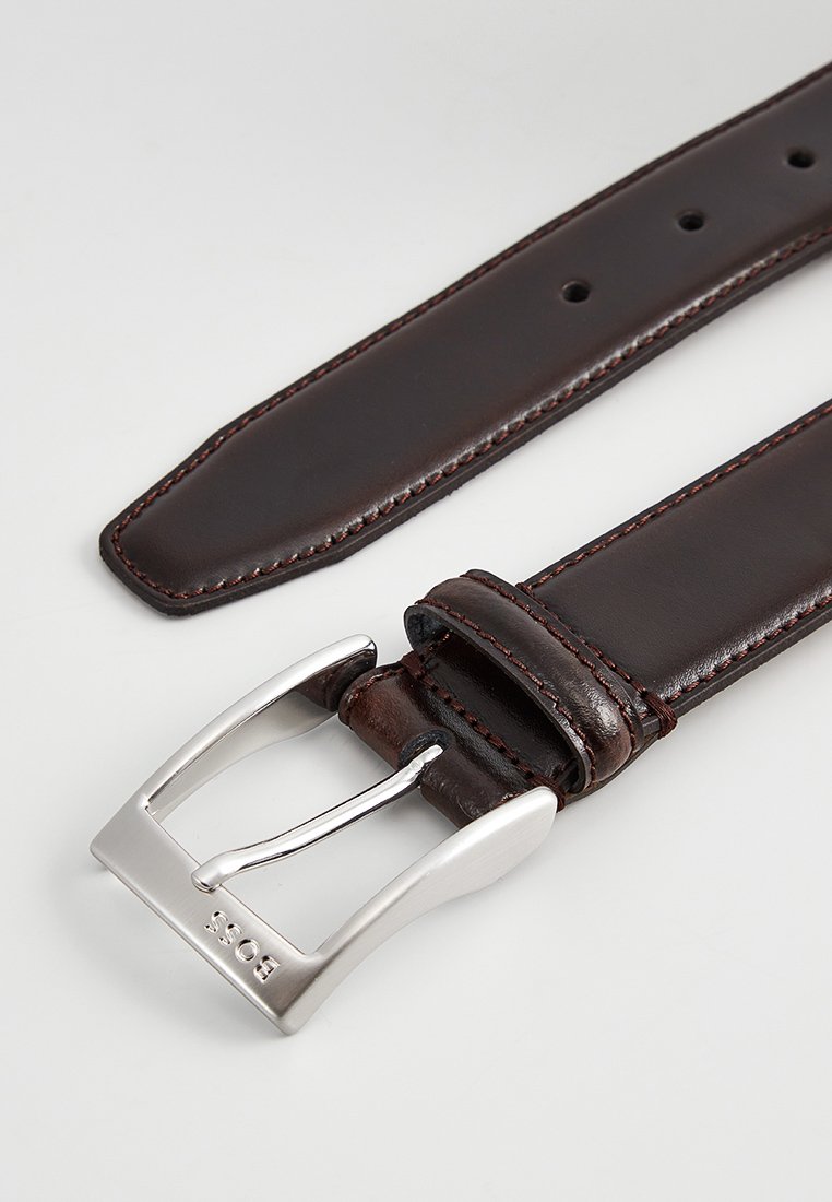Donkerbruine leren riem met zilveren metalen gesp, gegraveerd met "BOSS," voorzien van meerdere verstelgaten en gedetailleerde stiksels.