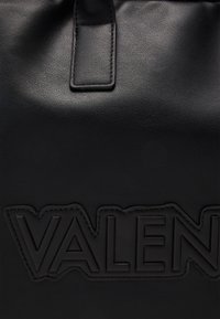 Musta nahkainen kassi, jossa on kohokuvioitu "VALEN"-logo, sileä pinta ja jämäkkä muotoilu, jossa on huomattava kahva.