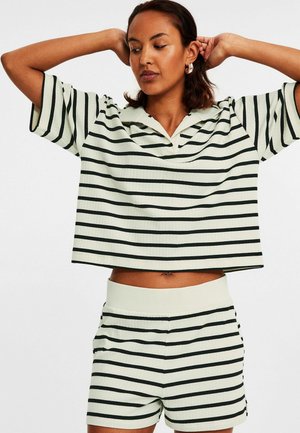 Stribet ribbet sæt i lys grøn med sorte vandrette striber. Oversized top med korte ærmer og krave, matchende shorts med elastisk talje.