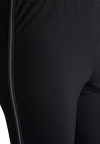 Zwarte legging gemaakt van rekbare stof, met een slim fit en een zilveren accentstreep langs de zijkant voor extra detail.