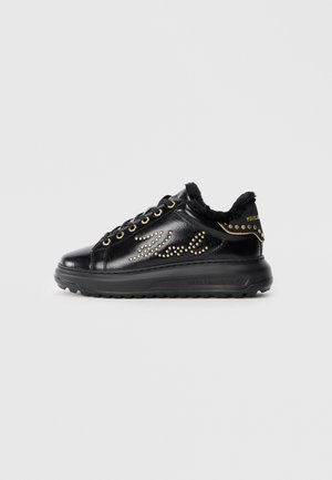 Black leather sneaker with fur lining, adorned with gold studs and a wave pattern. Features black rubber sole and gold hardware accents.