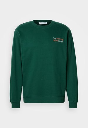 Sweatshirt verde escuro com decote redondo, mangas longas e punhos canelados. Apresenta "Sociedade do Café da Manhã Preguiçoso" bordado em laranja e branco.