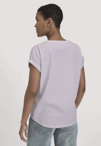 Lila katoenen t-shirt met omgerolde korte mouwen, een ronde halslijn en een losse pasvorm. Heeft een zachte textuur en een gebogen zoom.