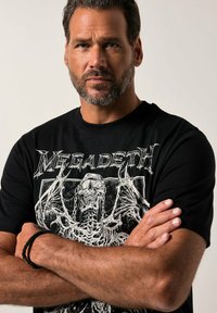 Černé bavlněné tričko s velkým bílým grafikou lebky a kosterního designu s textem "Megadeth" nahoře. Krátké rukávy, kulatý výstřih.