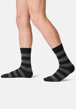 Schwarz und grau gestreifte Socken mit einem gerippten Bund, gefertigt aus weichem Stoff, mit gleichmäßigen horizontalen Streifen und einem Design bis zur Mitte der Wade.