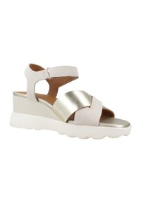 Sandalias de cuña con correas de ante beige y una banda cruzada metálica dorada. Suela de goma blanca con textura para mayor agarre y estabilidad.