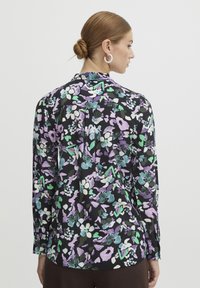 Long-sleeved blouse in multicolored floral pattern, featuring shades of purple, green, and white on a black background, with a button-down collar.