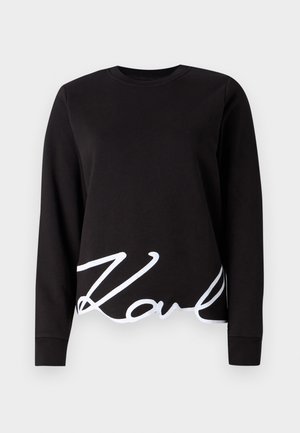 Black sweatshirt made of cotton, featuring long sleeves, a crew neckline, and a white script logo along the hemline.