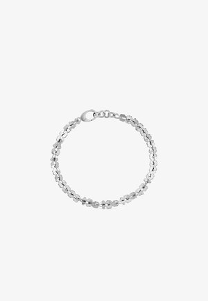 Pulsera de plata con pequeños eslabones en forma de trébol y cierre de mosquetón sobre un fondo blanco.