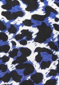 Musterstoff mit schwarzen und königsblauen Leopardenflecken auf einem weißen Hintergrund. Geschmeidige Textur mit verstreuten, dynamischen Pinselstrichen.