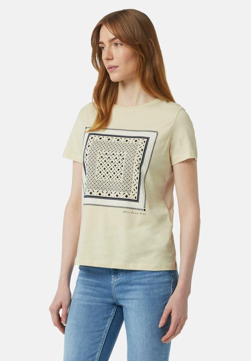 Crèmekleurig katoenen t-shirt met korte mouwen, voorzien van een vierkante geometrische print in donkerblauw en ingewikkelde patronen rond de randen.