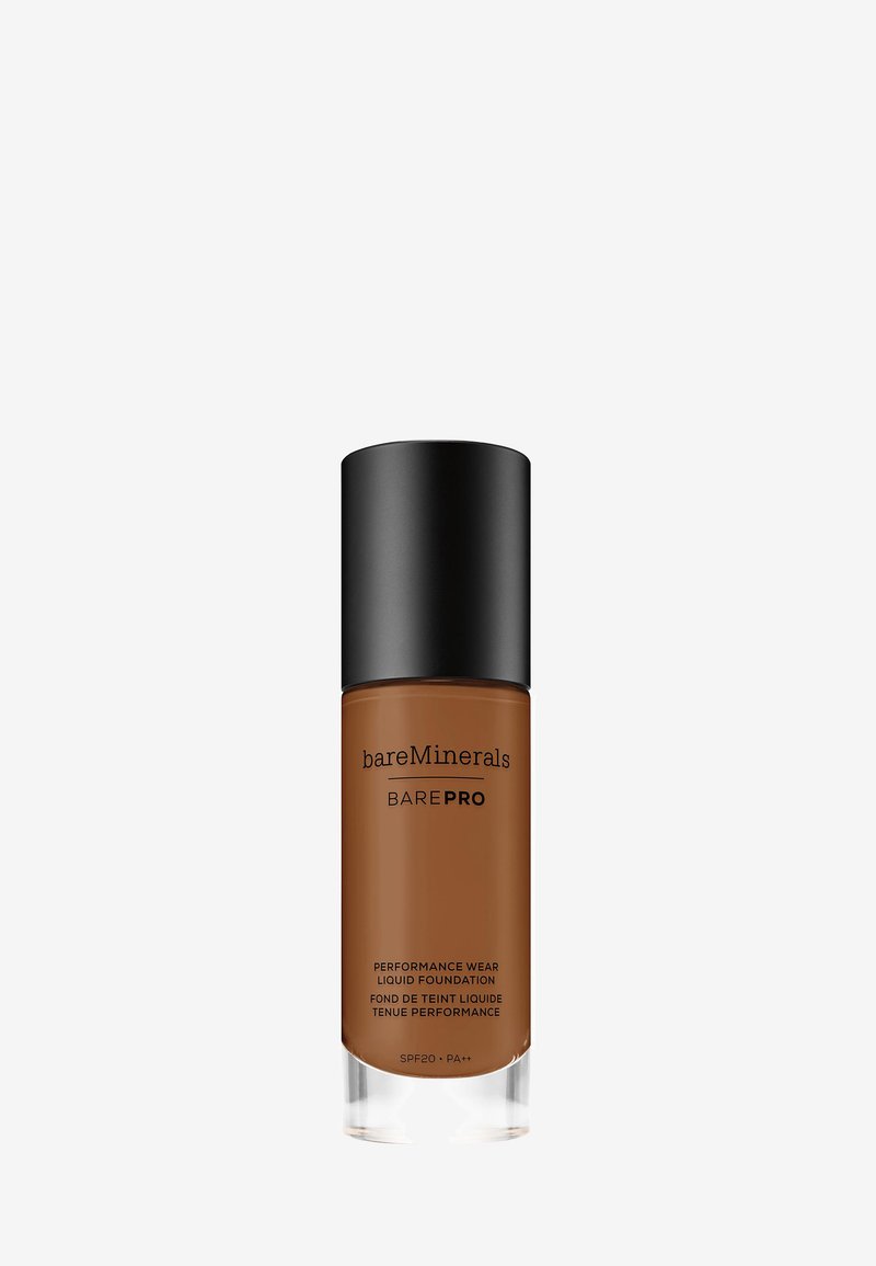 Fondotinta liquido marrone in una bottiglia di vetro trasparente con un tappo a pompa in plastica nera. L'etichetta lo identifica come bareMinerals BAREPRO. SPF 20.