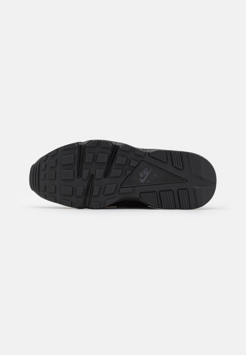 Schwarze Nike Air Schuhsohle mit strukturiertem Profil und Logo, das auf dem zentralen Bogen sichtbar ist, fotografiert auf einem weißen Hintergrund.