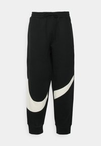 Czarne dresy z białym zakrzywionym wzorem na lewym nogawce, wykonane z miękkiego materiału, z elastycznym pasem i sznurkiem oraz ściągaczami przy nogawkach.