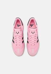 Pink athletic shoes feature a smooth upper with black stripes, a lace-up design, and a rubber outsole with a textured finish.