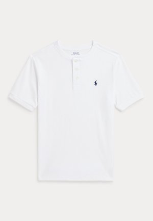 Polo alb cu mânecă scurtă, cu guler cu nasturi și un mic logo bleumarin pe partea stângă a pieptului. Material din bumbac neted, cu o tăietură clasică.