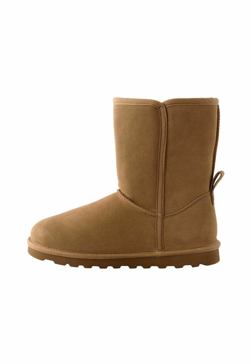 Tan suede ankle boot with a rounded toe, flat rubber sole, and stitched detailing. Features a pull tab at the back for easy wear.