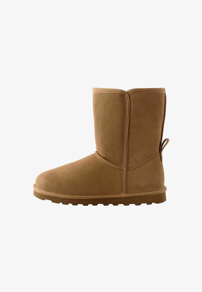 Beżowe zamszowe botki za kostkę z okrągłym noskiem, płaską gumową podeszwą oraz przeszyciami. Posiadają pętelkę z tyłu, co ułatwia zakładanie.