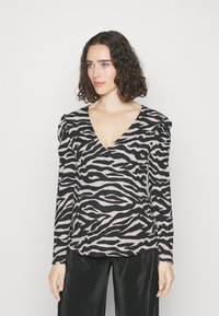 Haut à manches longues en v en motif zèbre rose et noir, avec des accents d'épaules froncés et un tissu texturé.