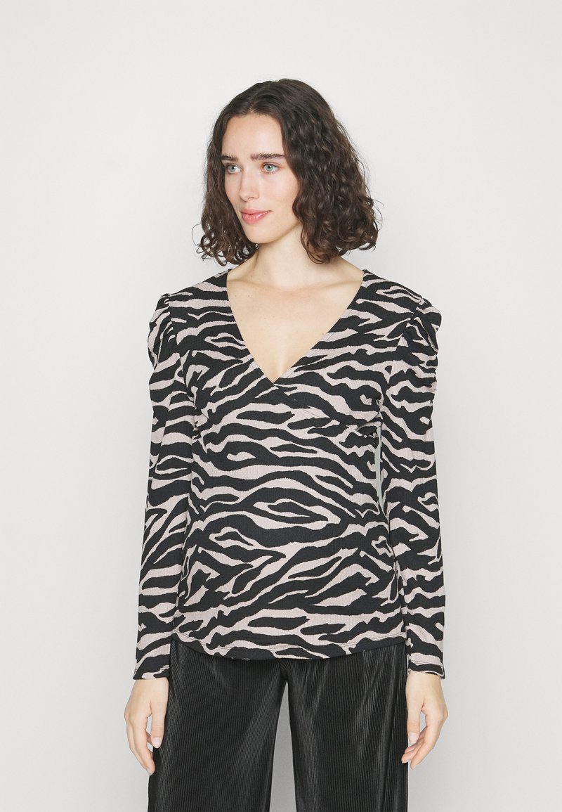 Haut à manches longues en v en motif zèbre rose et noir, avec des accents d'épaules froncés et un tissu texturé.