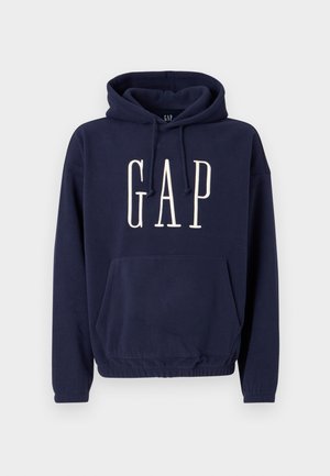 Tumesinine kapuutsiga pusa esetasku ja valge "GAP" logoga rinnal, millel on paelaga kapuuts ja elastne alumine serv.