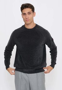 Maglione grigio scuro con scollo a girocollo e dettagli a coste sulle spalle, realizzato in un tessuto morbido. Orlo inferiore e polsini sono anch'essi a coste.