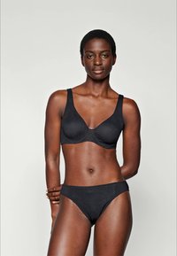 Zwarte beha en bikini-set van gladde stof, met een eenvoudig ontwerp, verstelbare bandjes en minimalistische patroondetails.