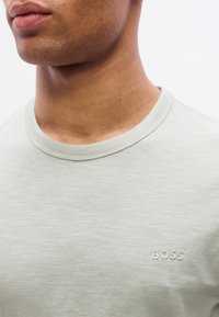 Ανοιχτό πράσινο κοντομάνικο T-shirt από απ αλό ύφασμα, με ριμπ λαιμόκοψη και ανάγλυφο λογότυπο "BOSS" στο αριστερό στήθος.