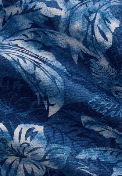 Blue fabric with a white and dark blue tropical floral pattern, showing texture and gentle folds.
