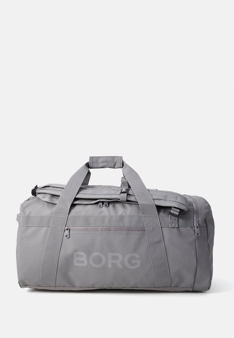 Sac de sport gris avec deux poignées et une bandoulière. Dispose d'un compartiment principal zippé et d'une poche avant. "BORG" imprimé sur le côté.