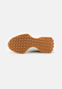 Semelle en caoutchouc avec un motif texturé et à pois orange, contrastant avec la partie supérieure blanche de la chaussure. Forme lisse et arrondie dans l'ensemble.