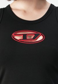 Schwarzes ärmelloses Oberteil mit einem rot gestickten Cutout-Design, das wie ein abstrakter Buchstabe "D" an der Brust unterhalb des Ausschnitts geformt ist.